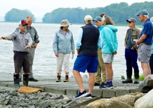 A geologist leads a group of people by the water.