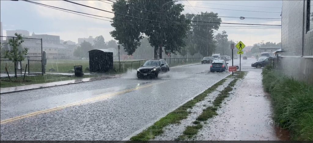 cars drive through flooded street