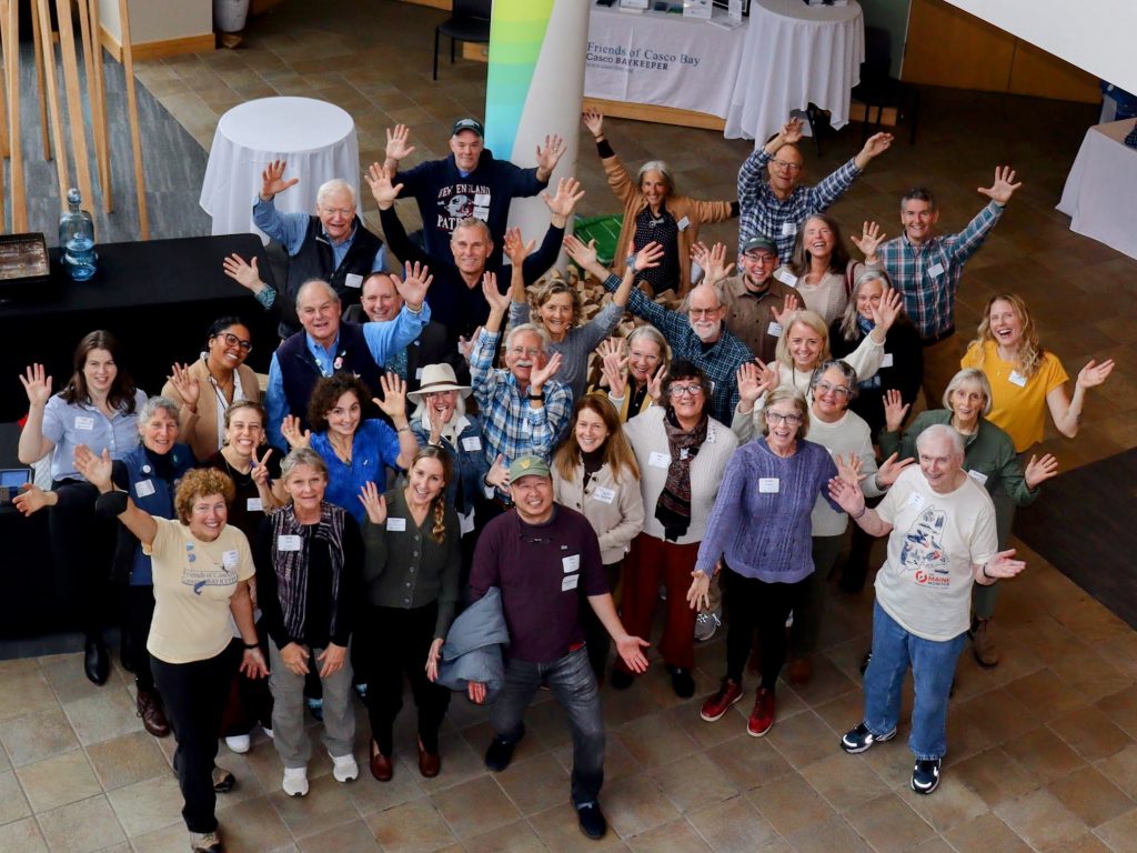 looking down from above at a large group of happy Film Fest for Casco Bay volunteers in a lobby