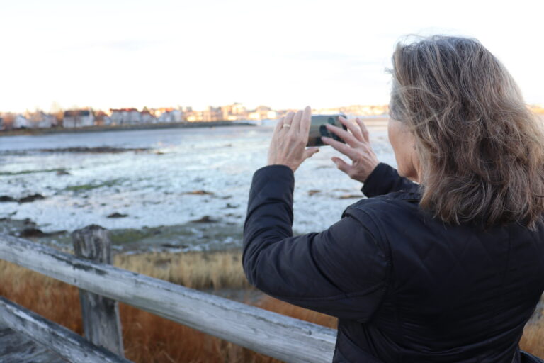a woman photographs an cove at low tide